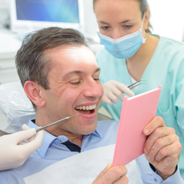 A man getting periodontal cleaning from dentists
